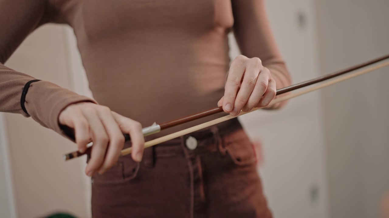 White coach demonstrating precise bow grip adjustment in studio, closeup hands showing fingertip placement and wrist alignment, thoughtful correction, calm teaching tone, emphasis on control and sound