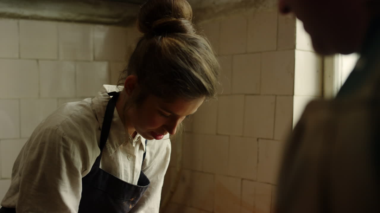 아름다운 여자가 도자기를 만드는 수공예품. 남자가 작업장에서 여자를 통제하는