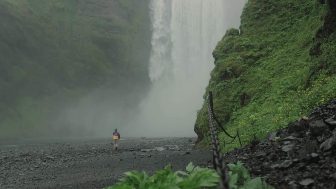 el hombre corre hacia la cascada en islandia