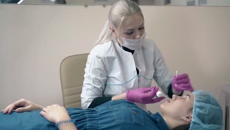 cosmetólogo aplica pintura en las cejas de la mujer en el salón