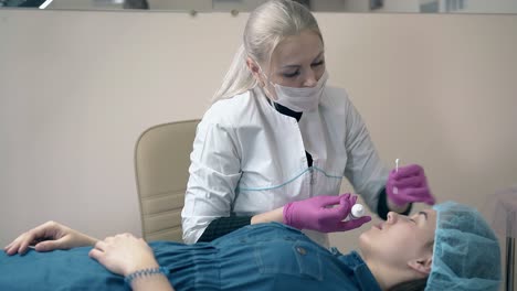 cosmetologist applies paint on woman eyebrows in salon