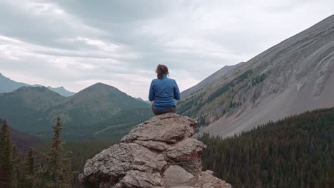 caminante sentado en la cornisa tomando fotos de las montañas se acercó a kananaskis alberta canada