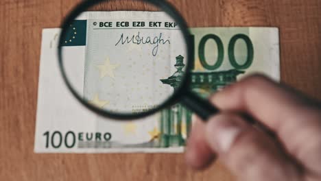 100 euro under magnifying glass