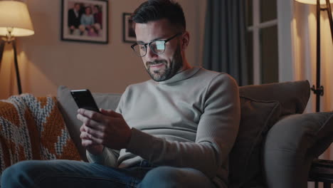 man using a smartphone on the couch in a living room