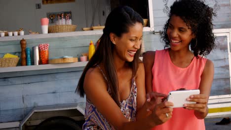 Friends-interacting-while-using-mobile-phone-at-counter