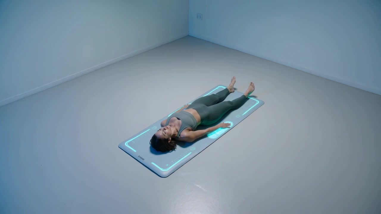 Settling woman wearing sportswear holding supine for cool-down in studio, smart LED mat cycling