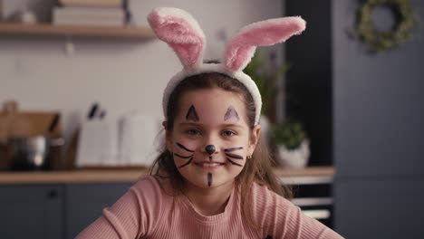 portrait of caucasian girl with painter easter bunny on face.