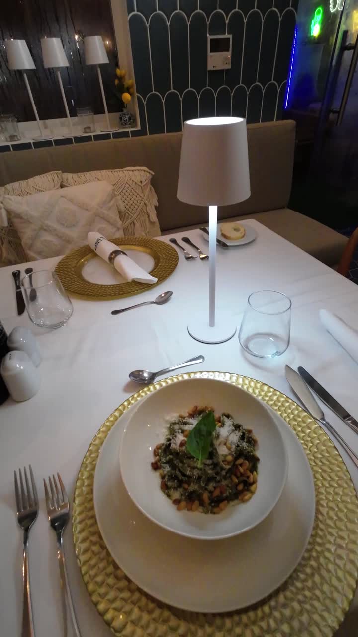 A beautifully arranged table awaits diners, featuring an enticing dish garnished with fresh herbs. The ambiance is warm and inviting, perfect for an enjoyable meal.