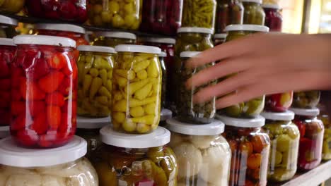 hand reaching for pickled peppers at a food stall