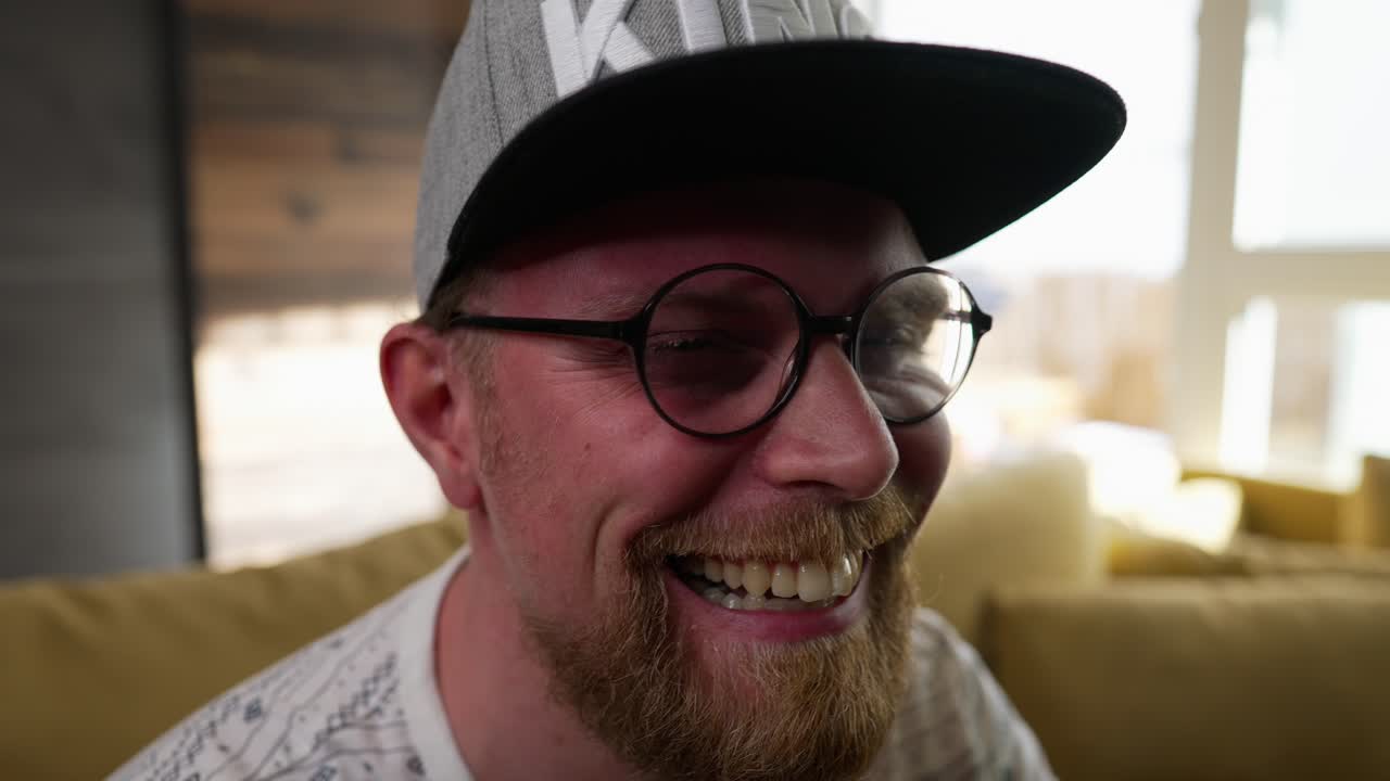 Man watching television, opens mouth in shock, laughs, zoom in