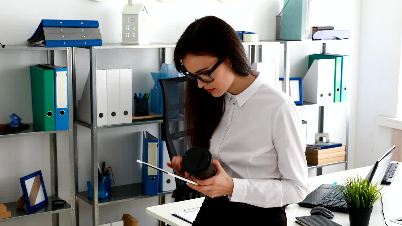 businesswoman using tablet and drinking coffee in modern office