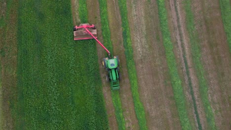 aerial harvest: green tractor mowing hay on a circular field in british columbia