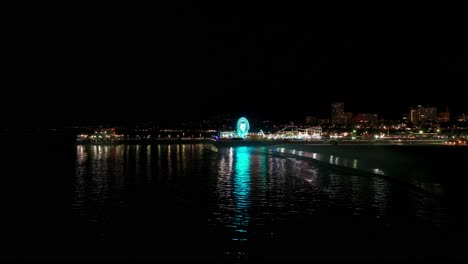 Nighttime-drone-shot-flying-backward-revealing-Santa-Monica-Pier