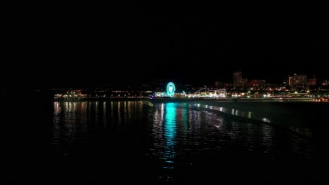 una toma nocturna de un dron volando hacia atrás revelando el muelle de santa mónica.