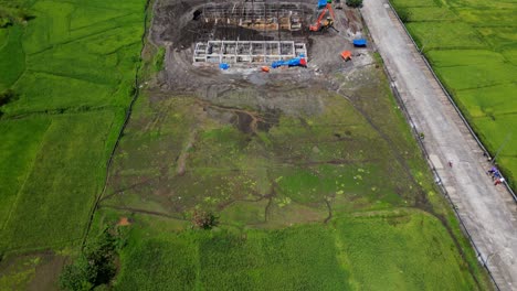 green meadow reveals building construction site near rural village in malilipot, albay philippines. aerial tilt-up shot