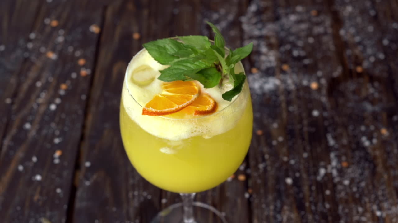 Et glas gul lemonade med mynte på en træoverflade