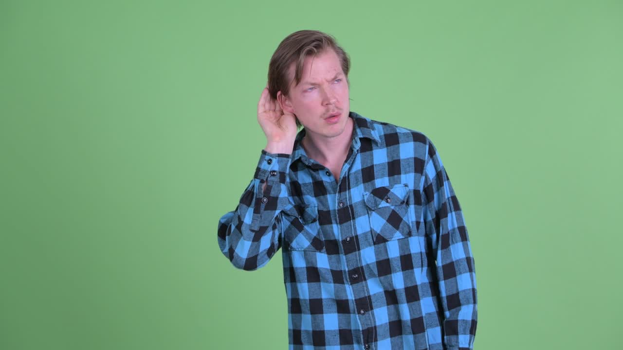 Portrait of Caucasian man listening curiously shot against green studio background