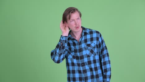 Portrait of Caucasian man listening curiously shot against green studio background