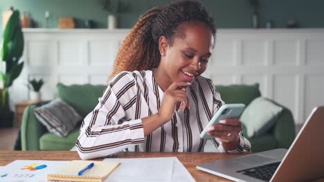 overjoyed young african american woman uses mobile phone for online shopping