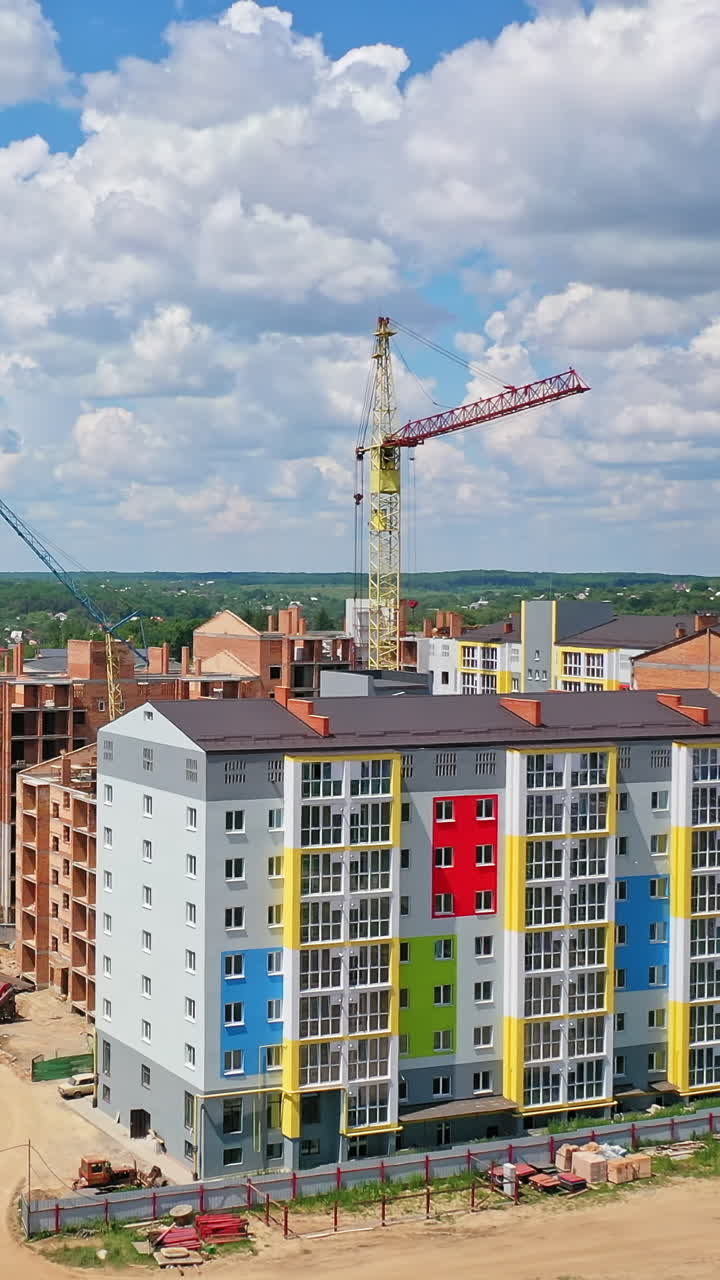 Building of a modern district. Construction site of new complex with high rise buildings. Colorful apartment building in new microdistrict. Vertical video