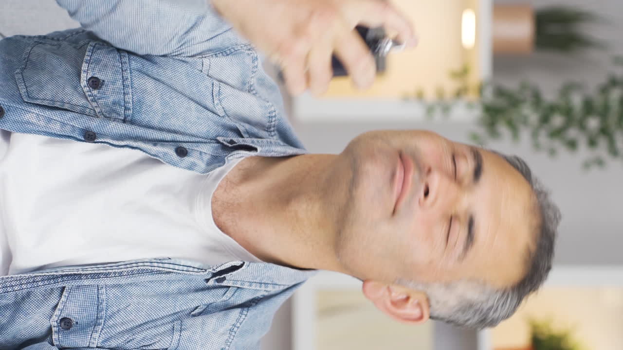 향수를 착용하고 좋은  ⁇ 새를 맡는 남자의 수직 비디오입니다.