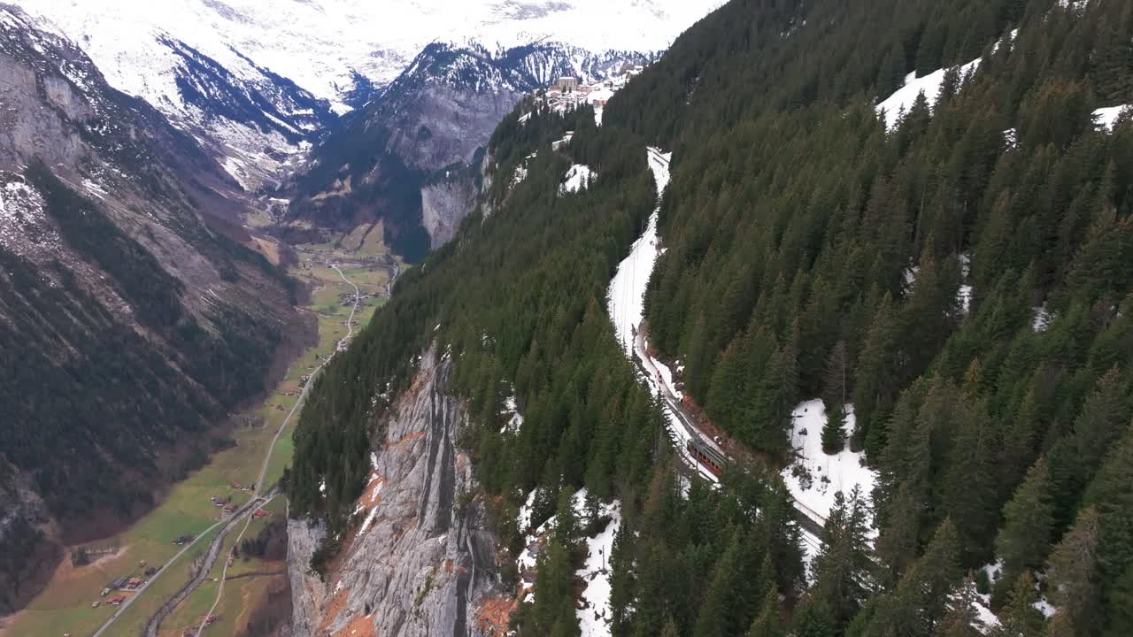 ferrocarril entre el bosque de hoja perenne y cerca de la escarpada orilla de la montaña suiza