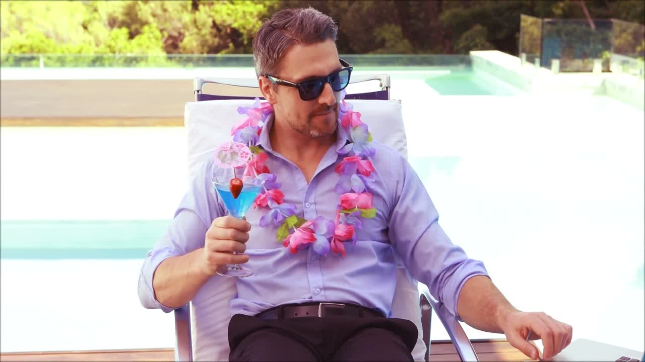 편안한 남자가  ⁇ 테일을 마시고 노트북을 사용합니다.