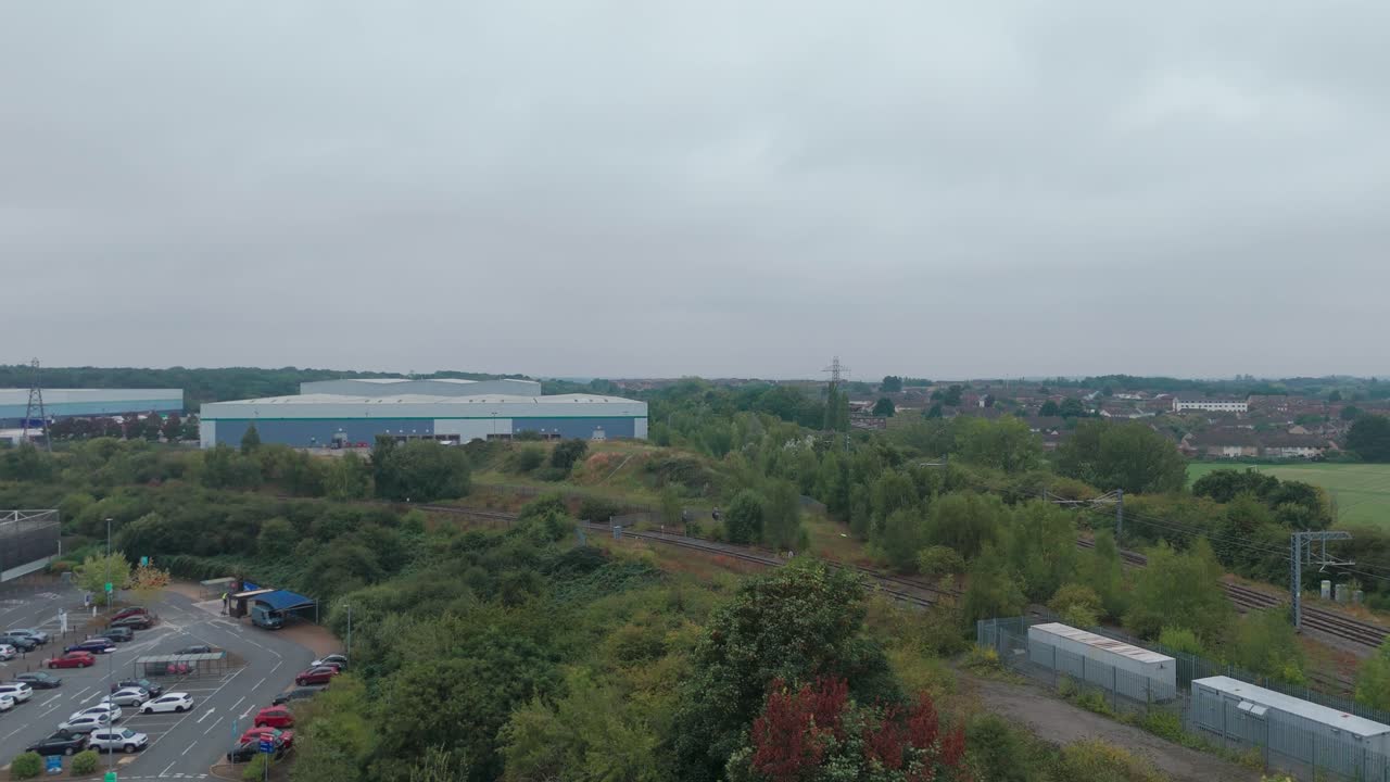 Urban landscape with an overcast sky, blending nature and industry, featuring trees, buildings, and a parking lot, showcasing the harmony between urban development and greenery