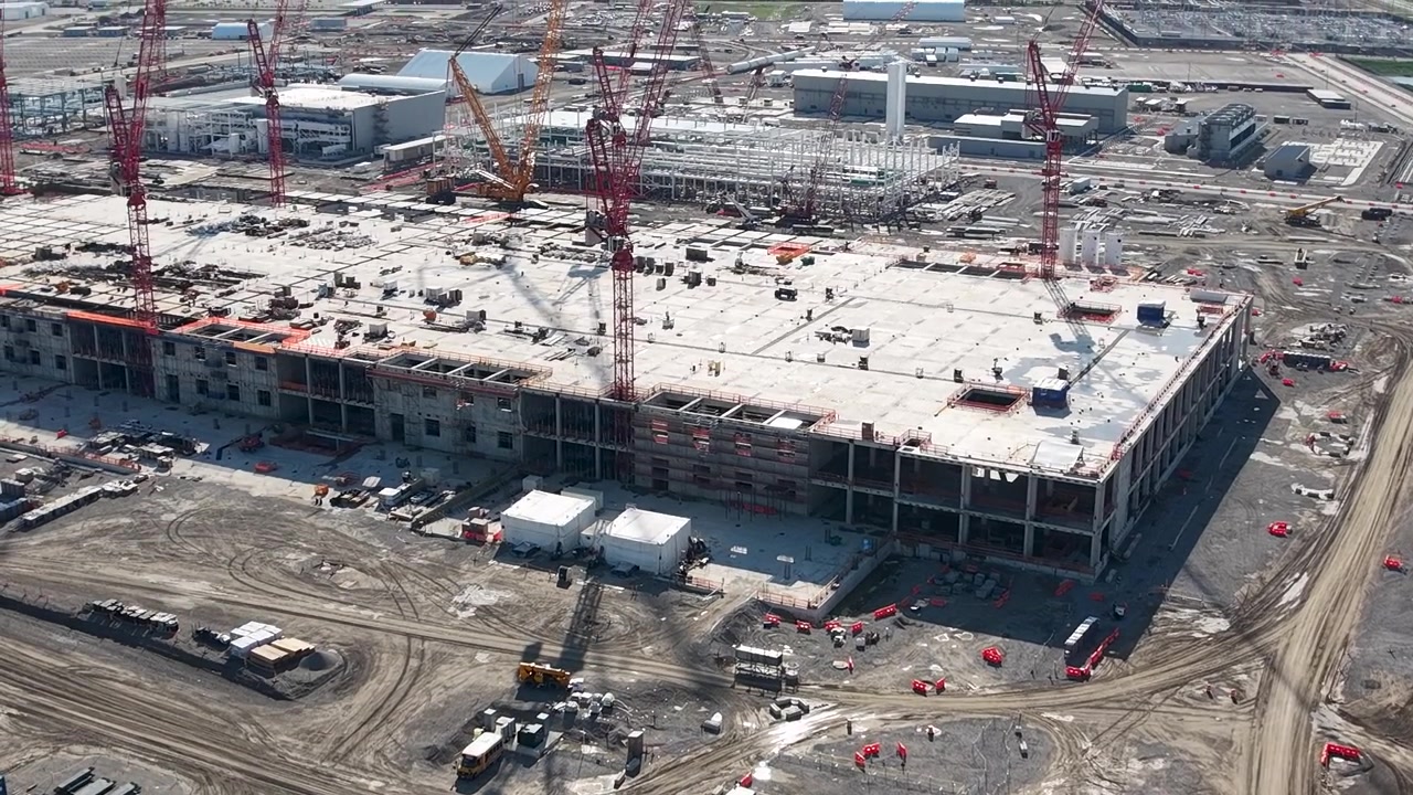 Drone view over the massive Intel chip factory construction site with vehicles and structural framing