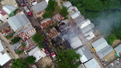 Aerial-view-above-a-collapsed-building-ruins,-smoke-rising,-firefighters-trying-to-quell-the-fire,-in-ghetto-Favela,-Rio,-Brazil,-South-America---screwdriver,-drone-shot