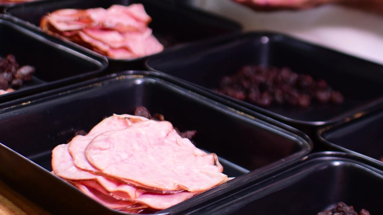 Kockhänder fördelar mat i cateringbehållare med grunt skärpedjup.