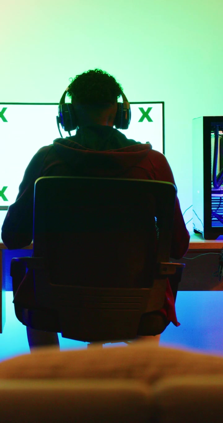 Giovane gamer che gioca ai videogiochi al computer in una stanza buia