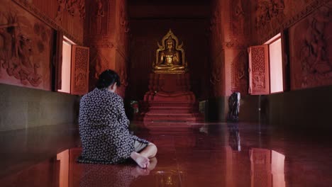 mujer asiática reza en el templo budista tailandés