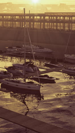 sunset at harbor with moored boats reflecting orange light