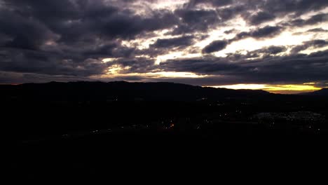 aerial drone hyperlapse clouds moving over mountain silhouette at sunset