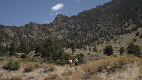 hikers walk along trail in colorado with rugged rocky mountains behind