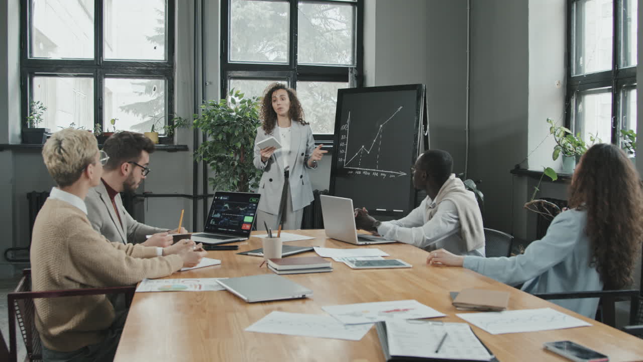 Female Investor Making Presentation at Chalkboard to Colleagues