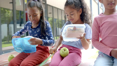 in school, three children sitting with lunchboxes and apple during break