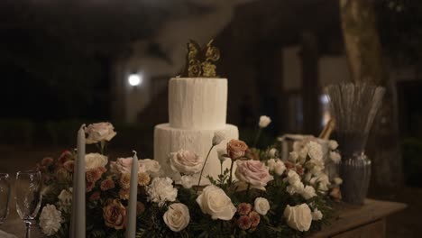 wedding cake decorated with flowers, surrounded by candles and champagne on a rustic table