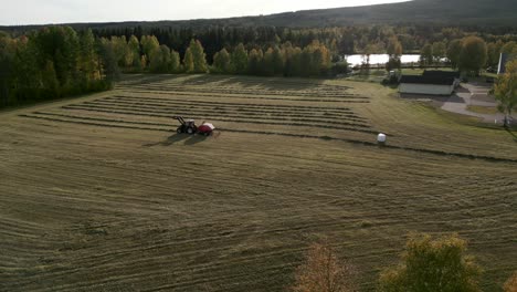 tractor collects dry hay on a sunny fall afternoon