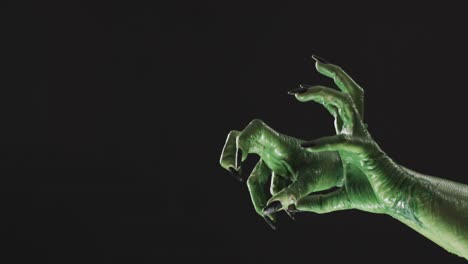Video-of-halloween-green-monster-hands-with-copy-space-on-black-background