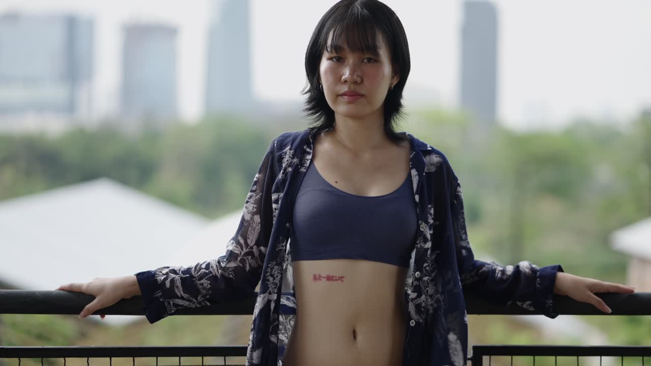 Young woman posing on a balcony with a city view