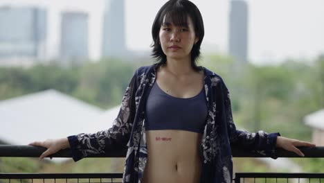 young woman posing on a balcony with a city view