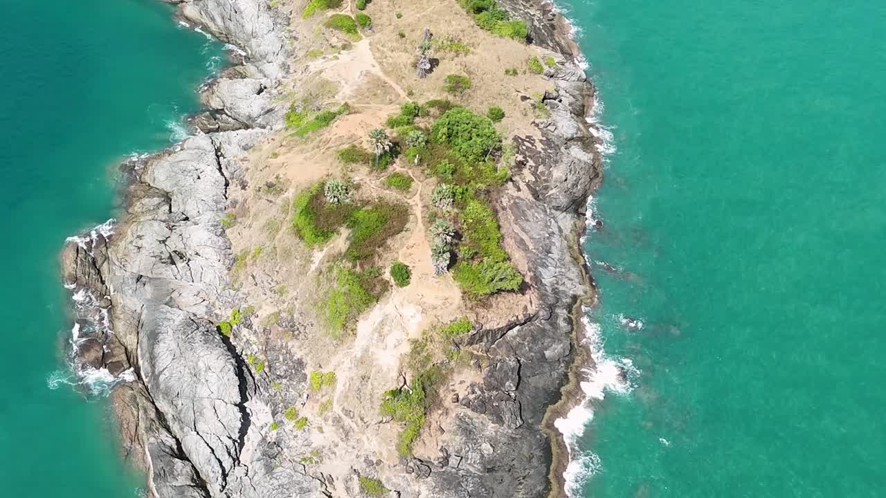 Aerial footage highlighting a rocky peninsula surrounded by vibrant turquoise waters and sparse greenery.