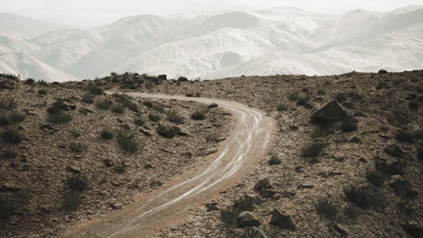 a winding dirt road leads through a desert landscape with mountains in the distance