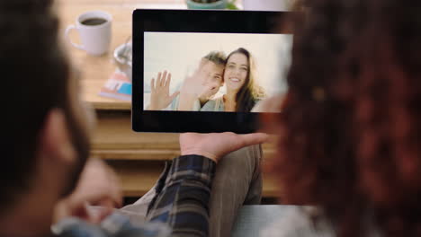 pareja en primer plano usando una tableta digital chateando por video con amigos en vacaciones viendo la pantalla de un dispositivo móvil disfrutando de la conexión relajándose en casa