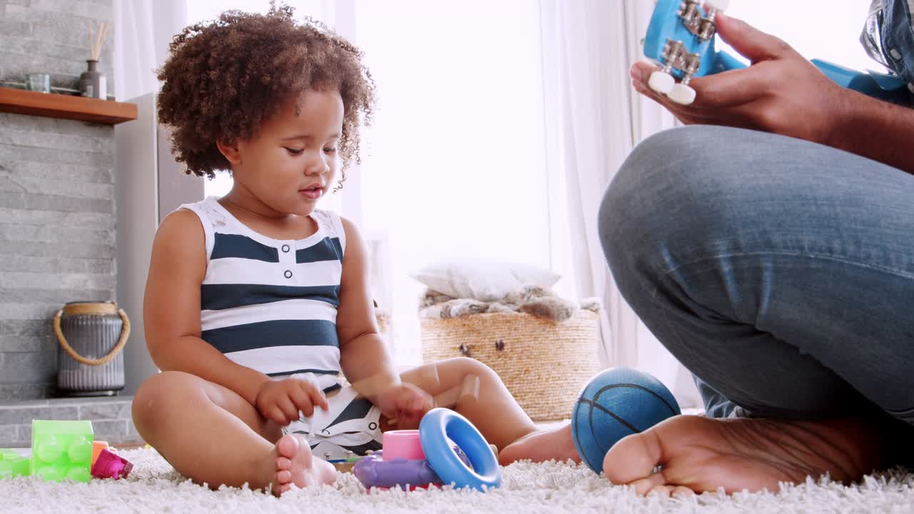 Young black girl playing xylophone with dad in sitting room