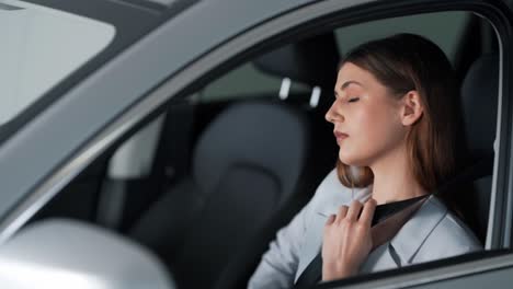 linda chica se pone el cinturón de seguridad sentado en un auto nuevo