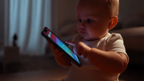 baby interacting with a smartphone in a dimly lit room