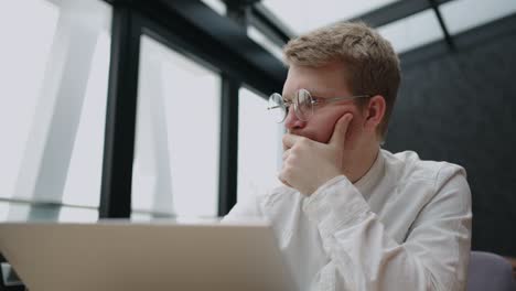 programmer or trader is working in office, sitting at table with laptop and thinking hard, financial crisis